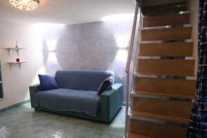 Un soggiorno con un divano, una scala e un muro con motivo geometrico.