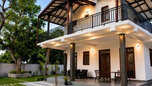 A two-story house with a balcony, a covered patio, and a garden. -  Araliya Villa- Luxury 3-Bedrooms, Private Pool & Sea Views. Breakfast Included. (Rekawa Road)