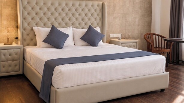 A large bed with a tufted headboard, two bedside tables, and a chair. -  Araliya Villa- Luxury 3-Bedrooms, Private Pool & Sea Views. Breakfast Included. (Rekawa Road)