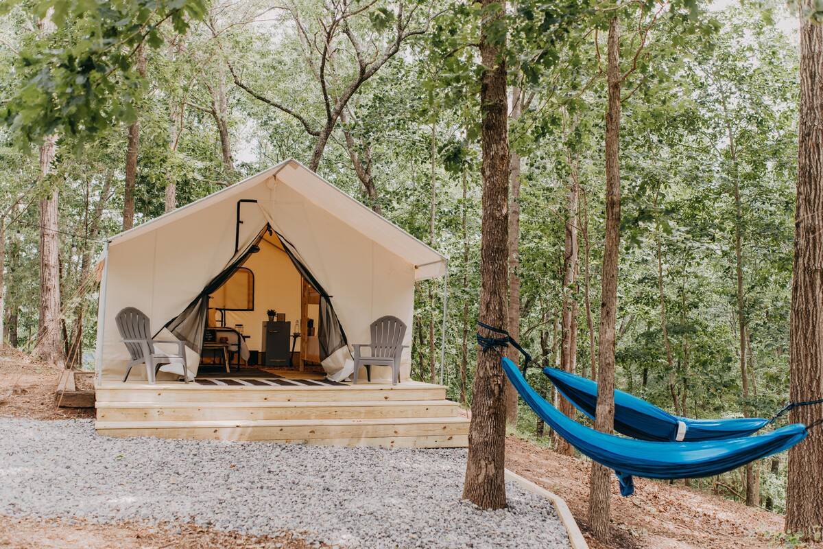 A tent-like structure with a porch, two chairs, and a hammock.