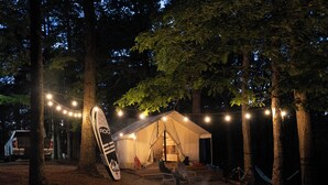 Una tienda de campaña con luces de cadena, una hamaca y una bicicleta.