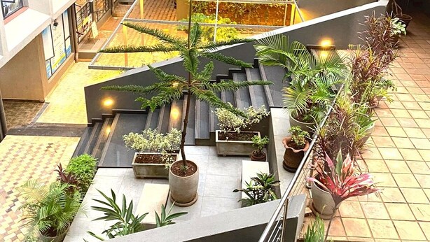 Ein mehrgeschossiges Innenhof mit Blumentöpfen, einer Sitzgruppe in der Mitte und einer Treppe.