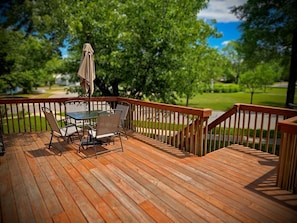 Eine Holzterrasse mit Gartenmöbeln und einem überdachten Tisch.