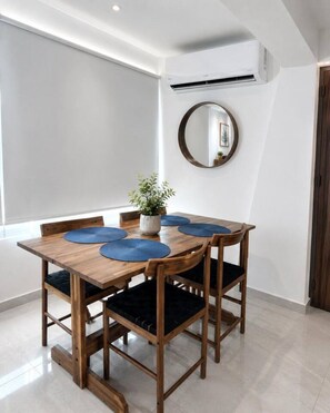Un comedor con una mesa de madera, individuales azules y sillas con cojines negros.