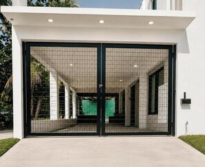 Ein moderner Gebäudeeingang mit Glastür, Betonweg und einem Briefkasten an der Wand.