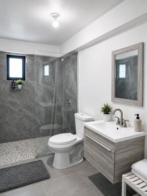 Un baño moderno con ducha, inodoro y tocador.