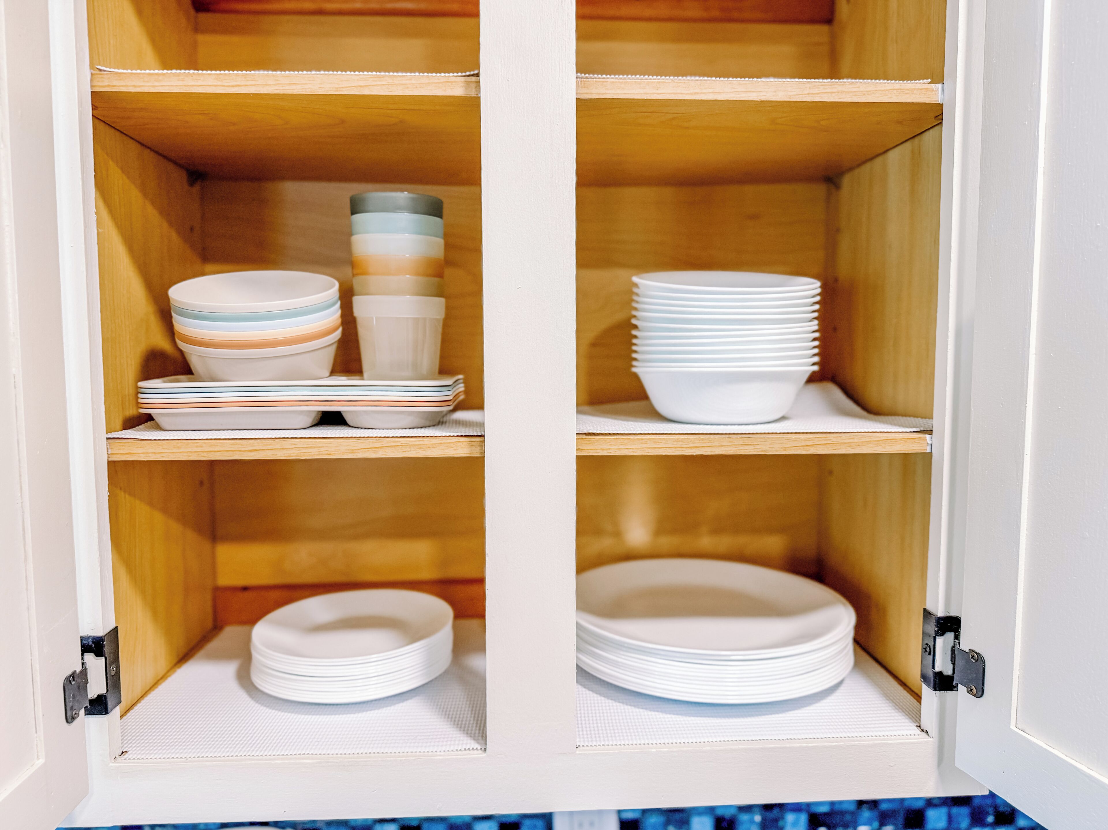 A cabinet with shelves containing stacked plates and bowls.