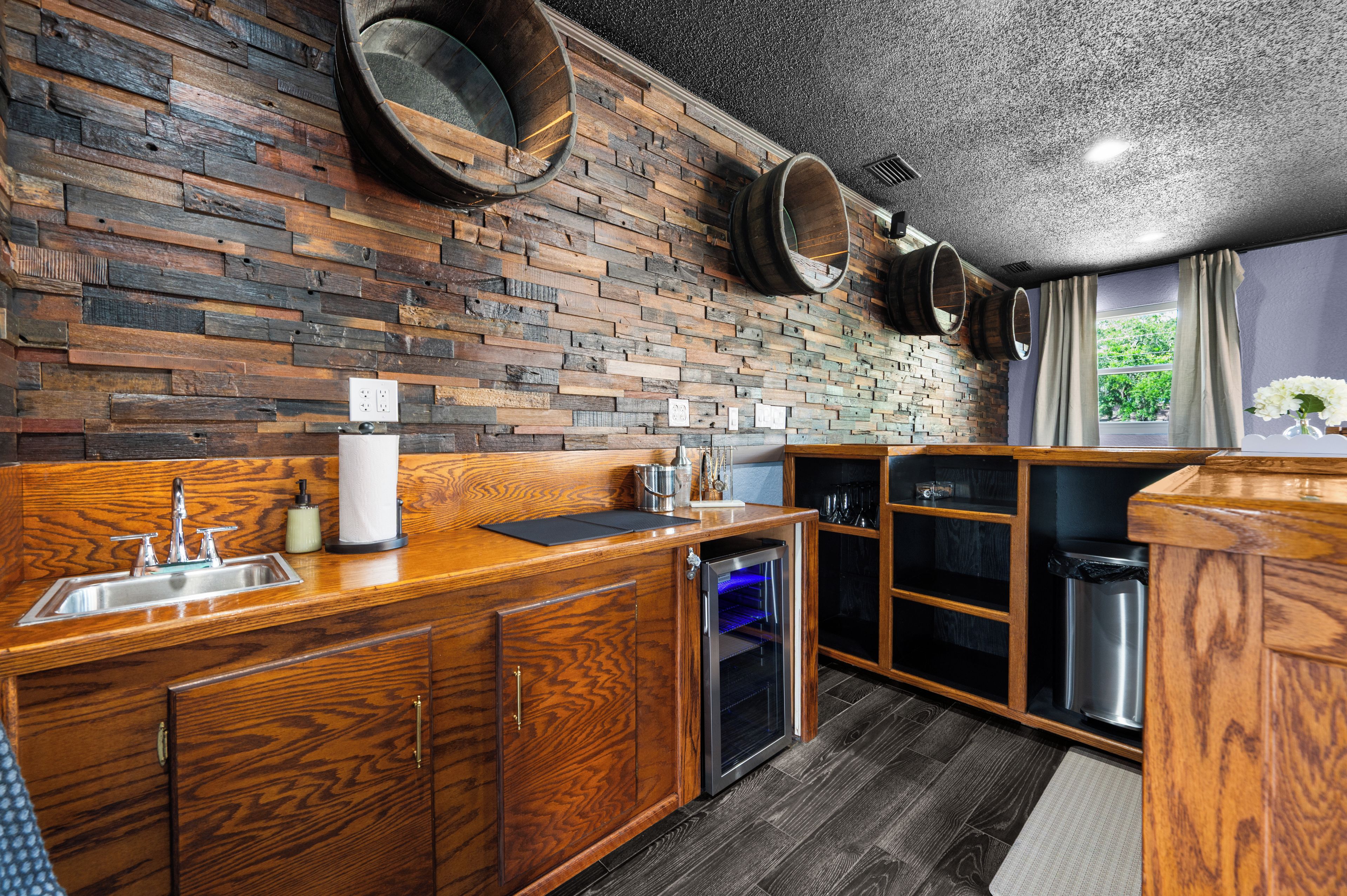 A kitchen with wooden cabinetry, a built-in dishwasher, and a window with curtains.