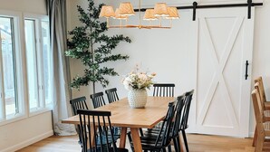 A dining area with a wooden table, black chairs, a potted plant, and a sliding barn door.