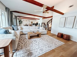 A spacious living room with a large sofa, a coffee table, and a patterned rug.