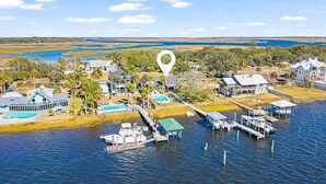 An aerial view of a waterfront property with a dock, boats, and a swimming pool.