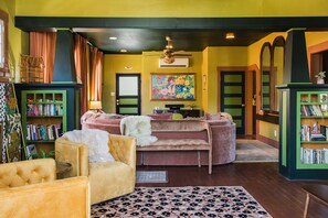 A cozy living room with a sofa, armchairs, a bookshelf, and a painting on the wall. - Casa Lita – Colorful Historic Home in the Railyard (Santa Fe)