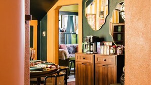 Un comedor con una mesa dispuesta para cuatro personas, una cafetera y un armario con utensilios de cocina.
