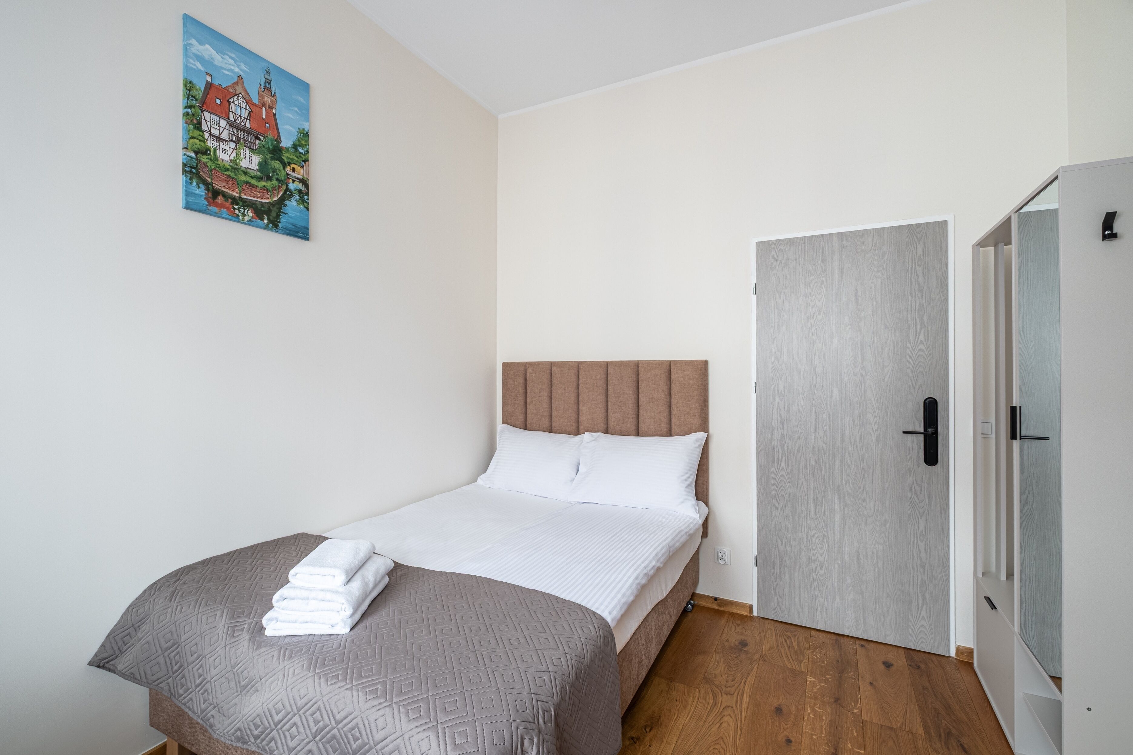 Un dormitorio con cama, una puerta y un cuadro en la pared.