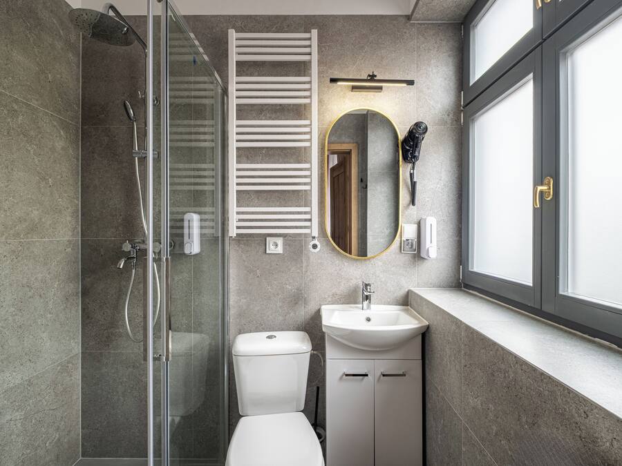 A modern bathroom with a glass shower enclosure, a toilet, a sink, and a vanity cabinet.