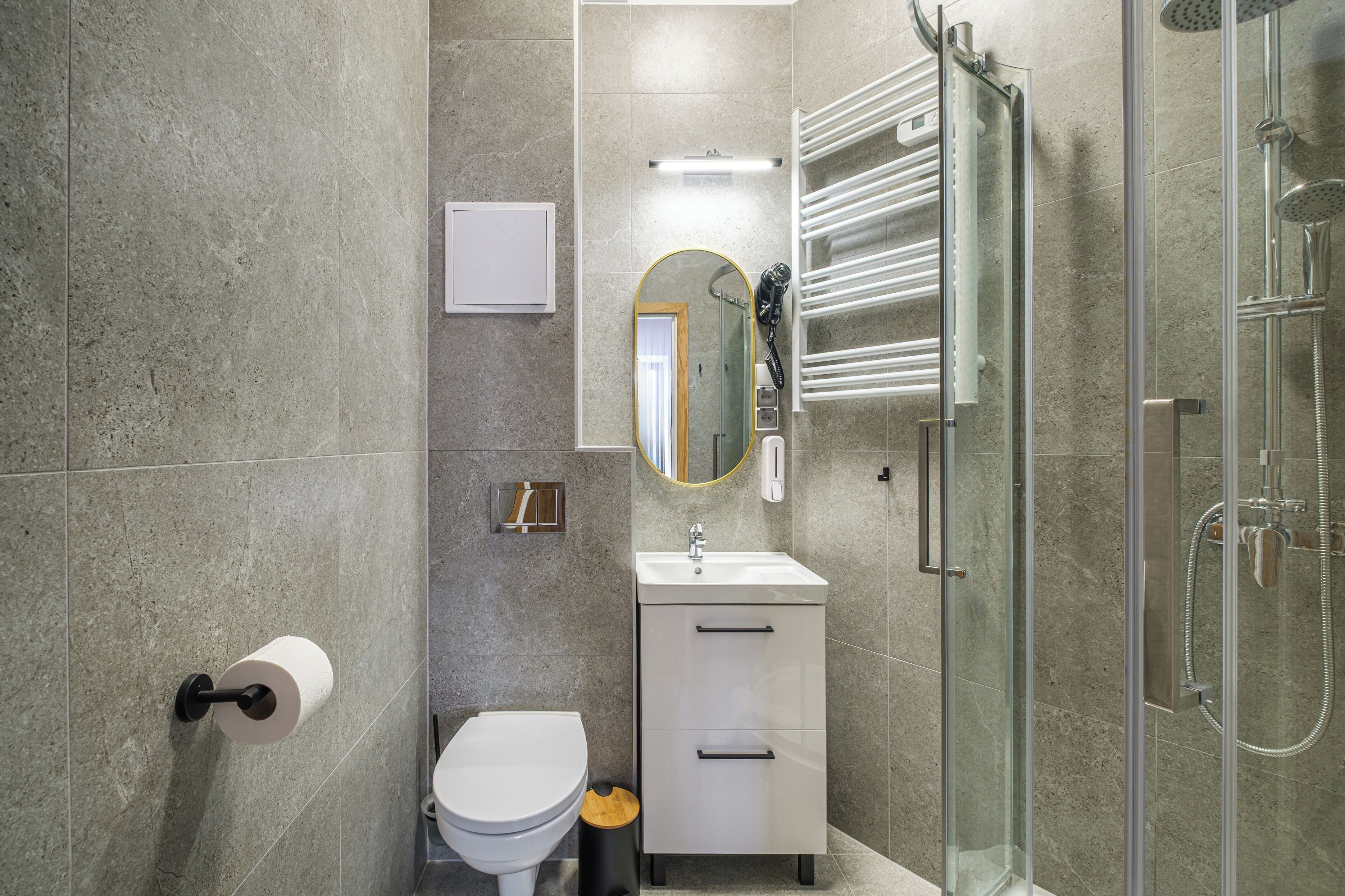 A modern bathroom with a toilet, sink, mirror, and shower.