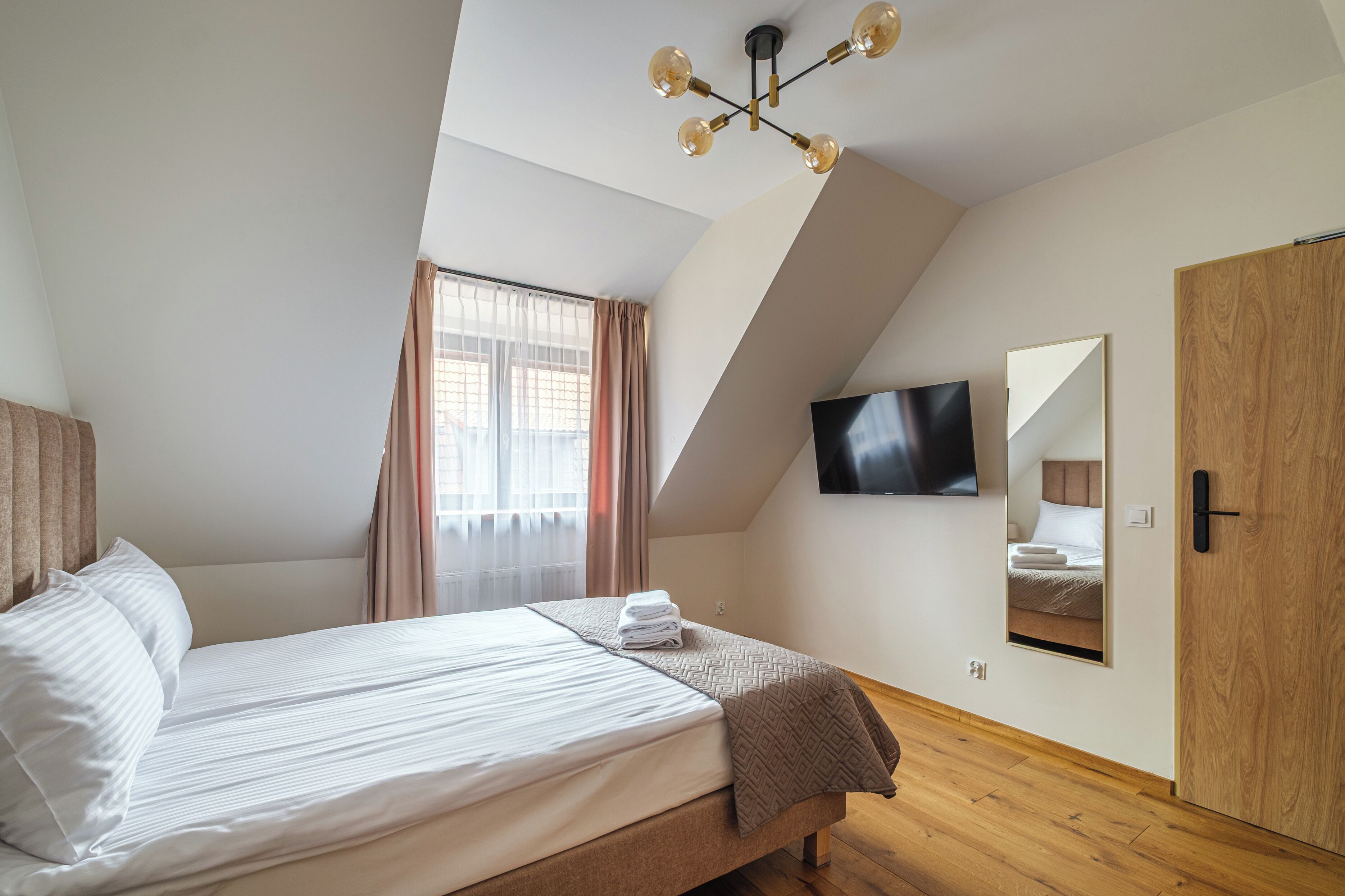 Une chambre à coucher avec un lit, une télévision, un miroir et une armoire en bois.