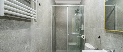 Un bagno moderno con cabina doccia in vetro, un water e un lavandino.