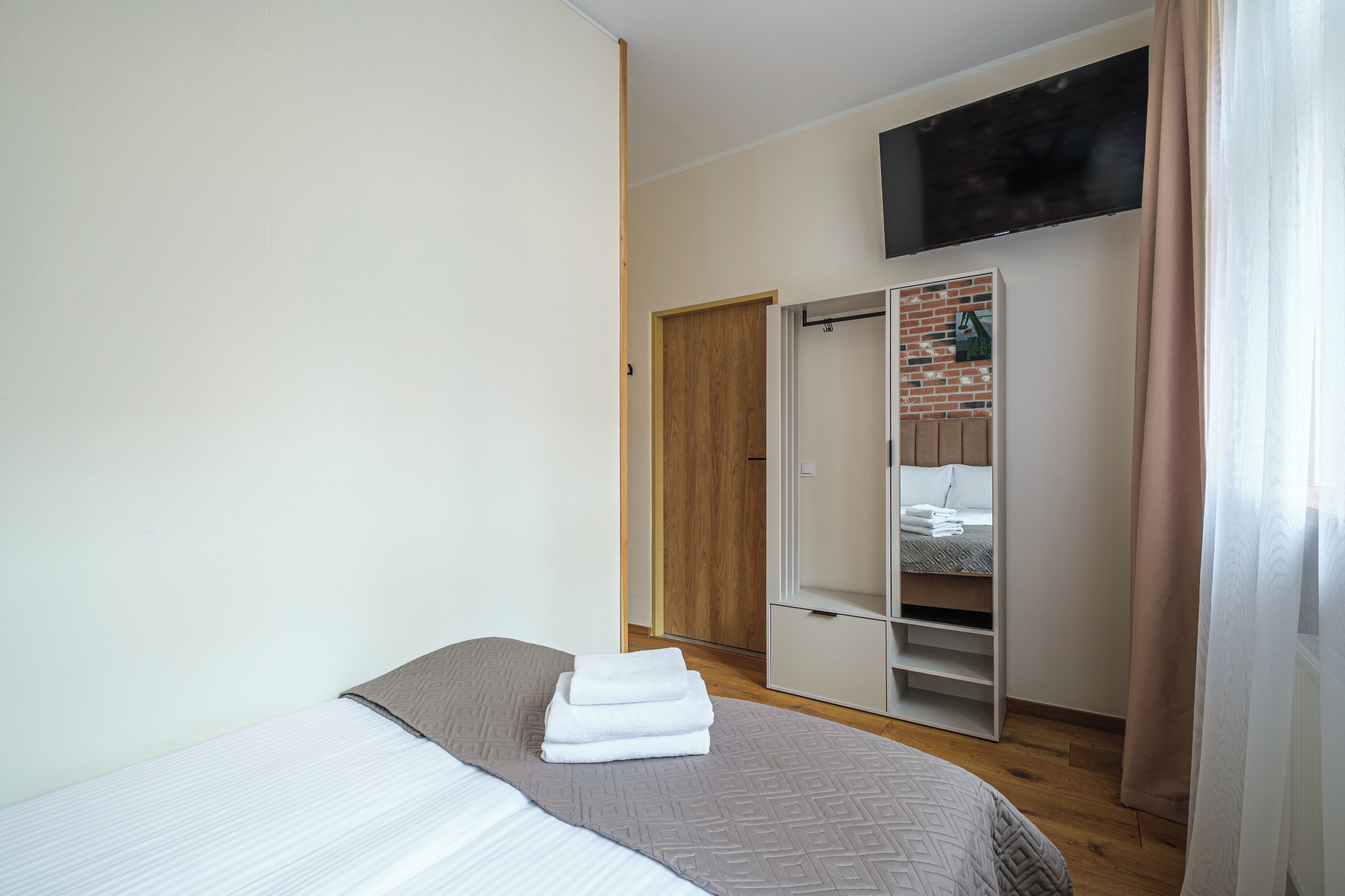 A bedroom with a bed, a wardrobe, and a mirror.