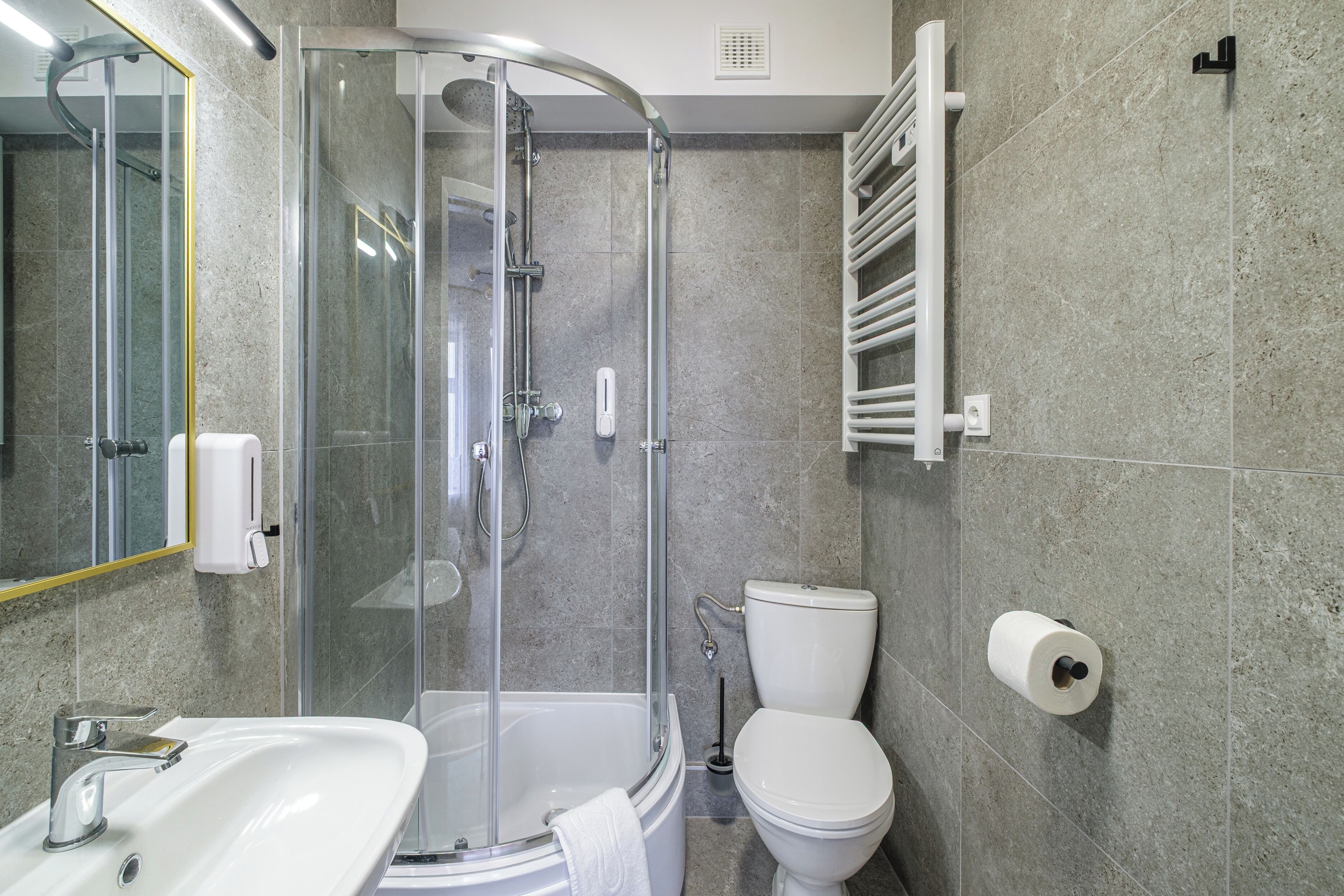 A modern bathroom with a glass-enclosed shower, a white sink, and a toilet.