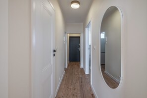 A narrow hallway with wooden flooring, white walls, and a door at the end.
