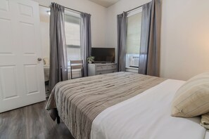 A bedroom with a bed, a TV on a dresser, and a door. - 3BR Fully Furnished House in Gary – Sleeps 6 (Gary)