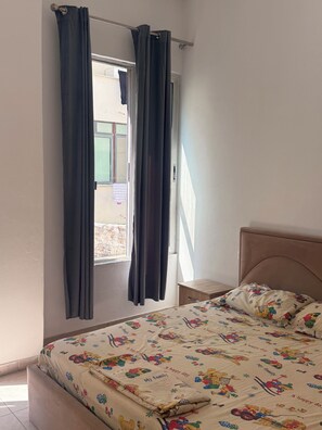 A bedroom with a bed, curtains, a window, and a view of the outside. - Xexi Apartments (Durrës)