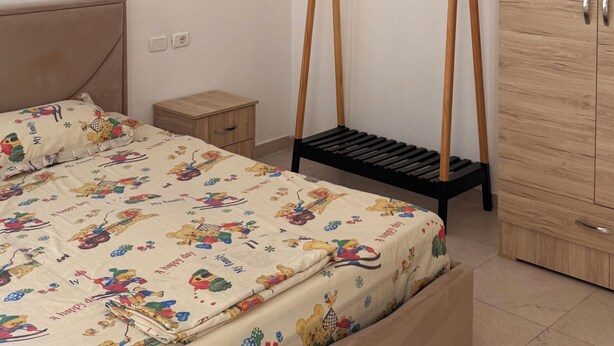Una camera da letto con un letto, un armadio in legno, un comodino e una parete decorata con stelle e nuvole.