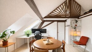 Un dormitorio tipo loft moderno con techo inclinado, una mesa de comedor de madera y una silla roja.