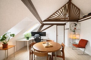 Ein modernes Schlafzimmer im Loft-Stil mit schrägem Dach, einem Holzesstisch und einem roten Stuhl.