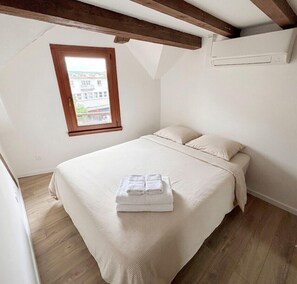 Ein Schlafzimmer mit Bett, Fenster und Holzbalken.