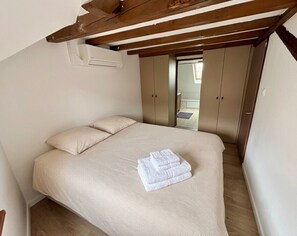 Ein Schlafzimmer mit Bett, Holzboden und Kleiderschrank.