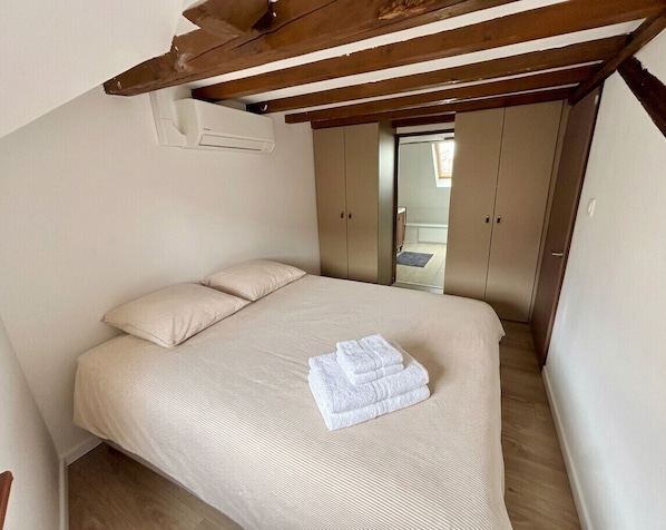 Ein Schlafzimmer mit Bett, Holzboden und Kleiderschrank.