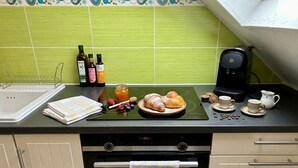 Una cocina con salpicadero de azulejos verdes, una cafetera, un tostador y varios productos para el desayuno sobre la encimera.