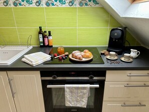Eine Küche mit grüner Fliesenwand, einer Kaffeemaschine, einem Toaster und verschiedenen Frühstücksangeboten auf der Arbeitsplatte.