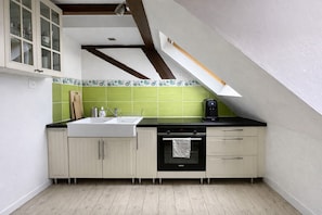 A kitchen with a white countertop, a sink, a stove, and a green backsplash. - The Gentle Haven: Cosy Apartment in Strasbourg (Strasbourg)