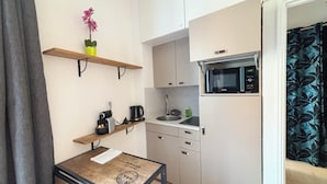Una cocina compacta con microondas, cafetera y una pequeña mesa con una planta.