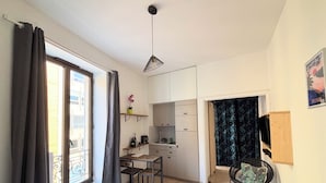 Una habitación compacta con cama, escritorio, silla y una pequeña zona de cocina.