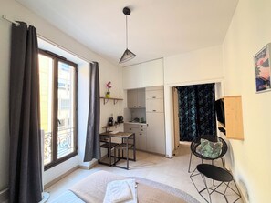 Ein kleines Zimmer mit Bett, Schreibtisch, Stuhl und einer kleinen Küchenzeile.