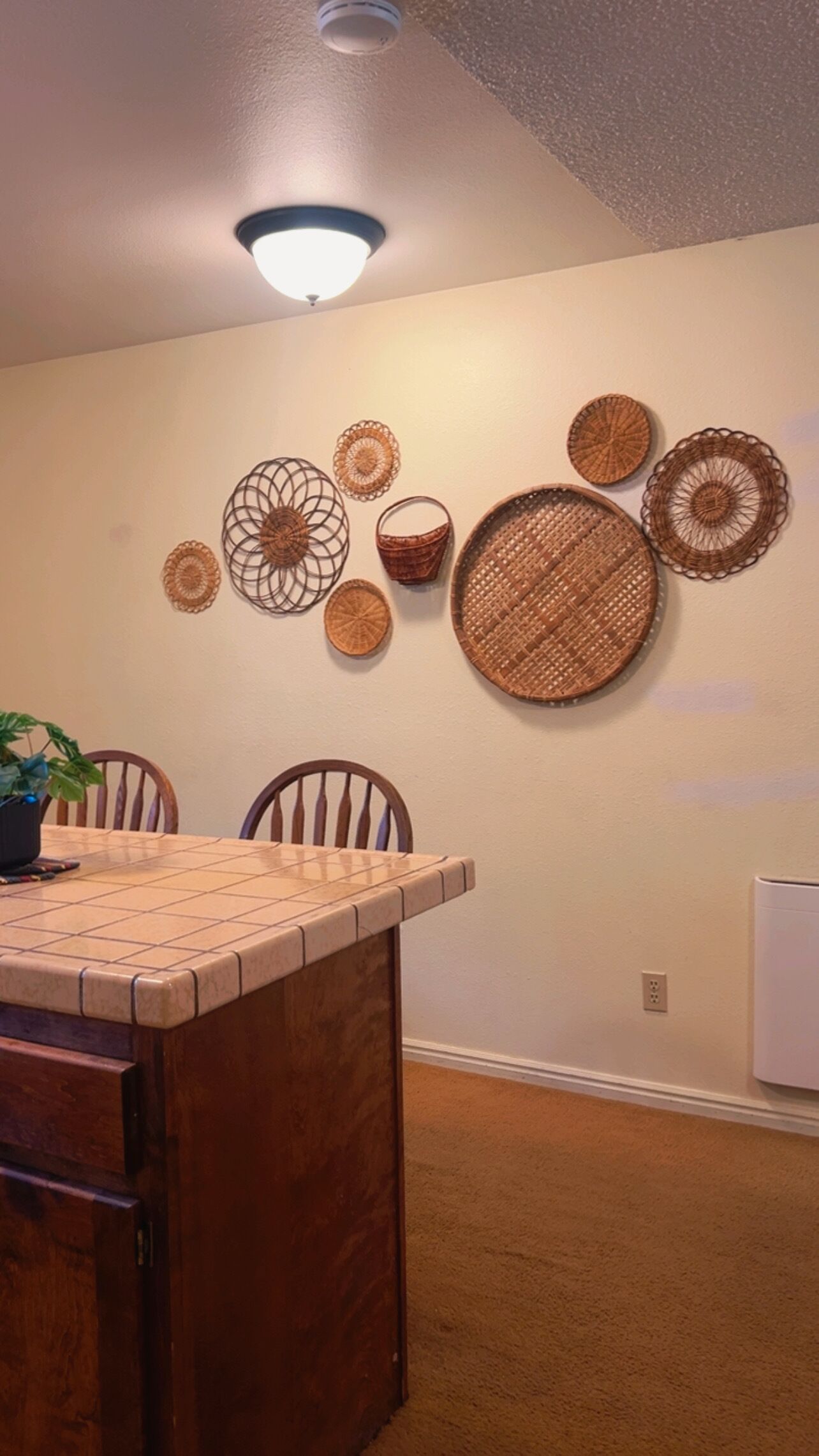 Ein Essbereich mit Holztisch und Stühlen, einer Deckenleuchte sowie an der Wand befestigten gewebten Körben.