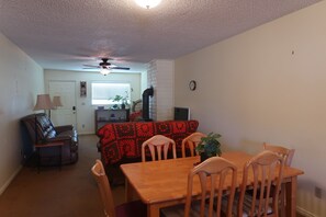 A living room with a fireplace, a dining table with chairs, a sofa, and a ceiling fan. - Cozy 2-bedroom condo in peaceful Parowan (Parowan)