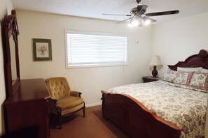 A bedroom with a bed, a chair, a nightstand, a lamp, a ceiling fan, and a window with blinds. - Cozy 2-bedroom condo in peaceful Parowan (Parowan)