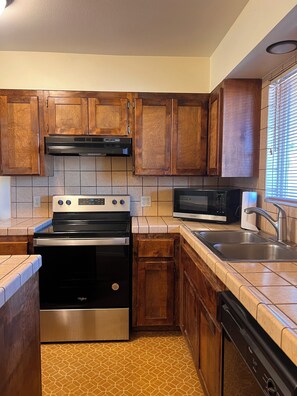 A kitchen with wooden cabinets, a stainless steel stove, a microwave, and a dishwasher.