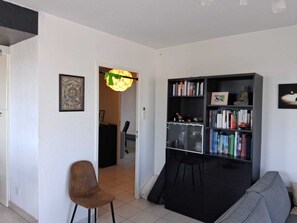 Ein Wohnzimmer mit Bücherregal, einem Sessel und einer Couch.