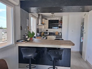 Eine moderne Küche mit Bar, einem Fenster und Blick auf die Stadt.