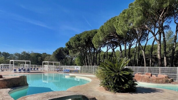 A swimming pool with clear water, surrounded by trees and a white fence. - Chalet in a 5-star resort with swimming pool (Puget-sur-Argens)