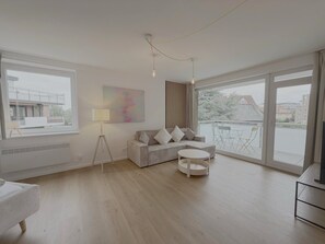 Ein stilvolles Wohnzimmer mit einer Couch, einer Lampe und Blick ins Freie.