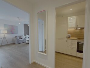 Ein modernes Interieur mit Wohnbereich, Küche und einem großen Spiegel.