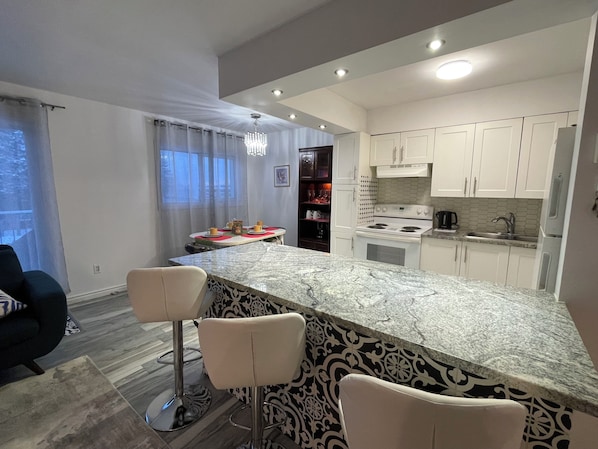 A modern kitchen with white cabinets, a marble countertop, and a gas stove.