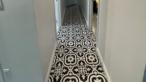 A hallway with patterned flooring, white walls, and doors leading to other rooms. - Spacious newly renovated two bedroom apartment (Sault Ste. Marie)